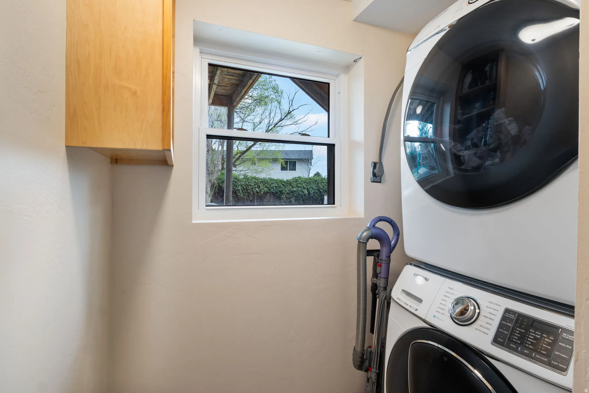 Utility space featuring a single-hung window, light wood-finish cabinetry, and a neutral wall color