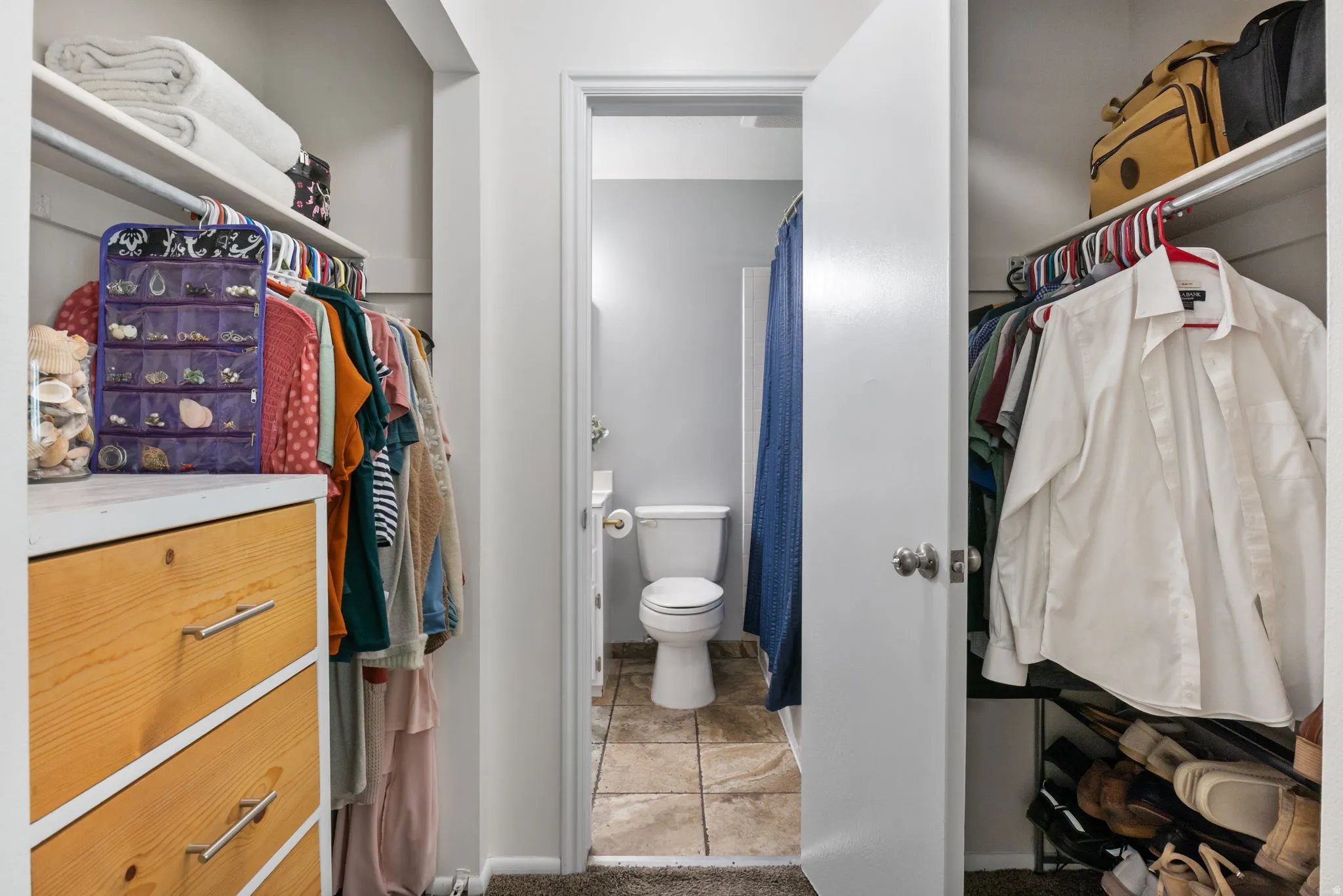 Wardrobe area featuring built-in shelving, hanging rods, and a wood-finish drawer unit