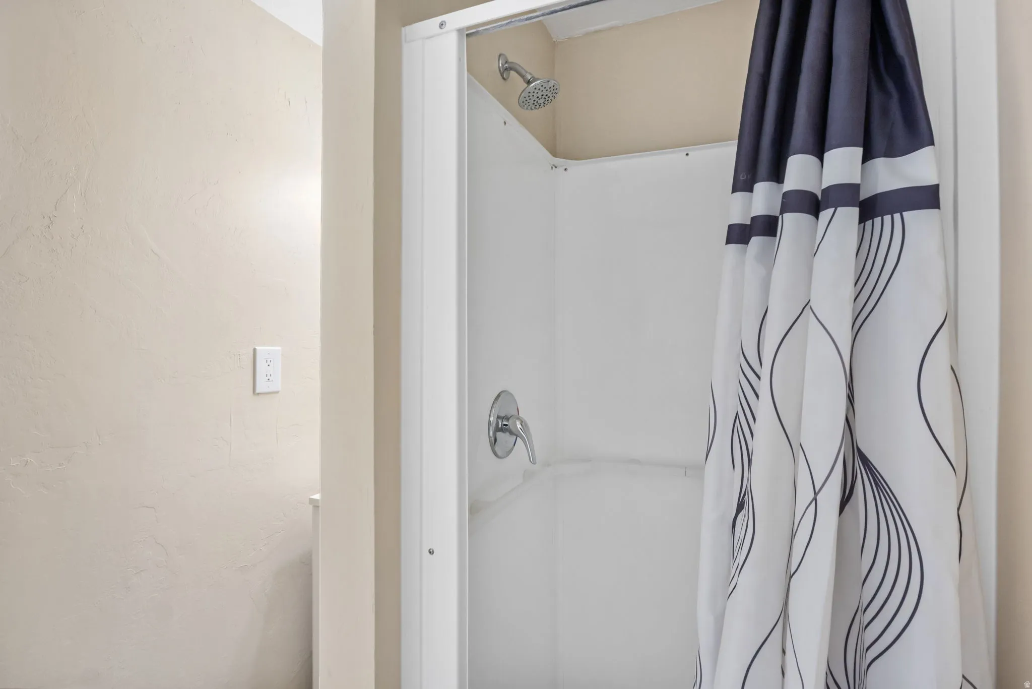 White shower stall with a chrome shower head and single-handle faucet