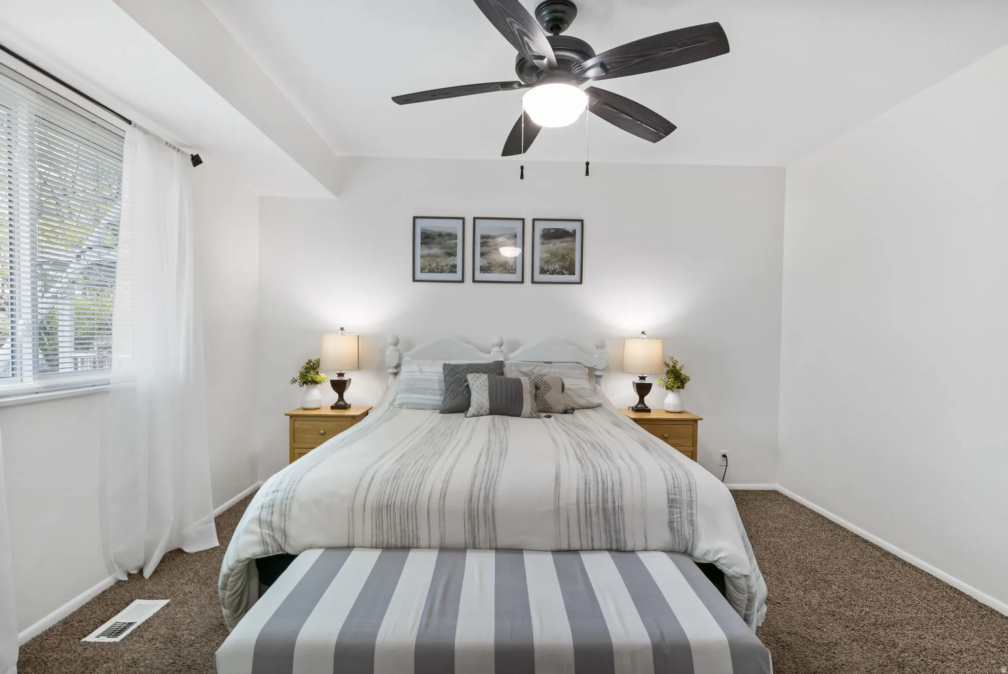Bedroom featuring neutral-toned carpeting, a ceiling fan with integrated lighting, and white walls
