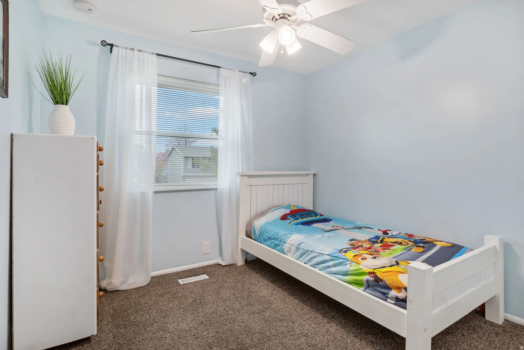 Room featuring light blue walls, a ceiling fan with integrated lighting, and a window with blinds and sheer curtains