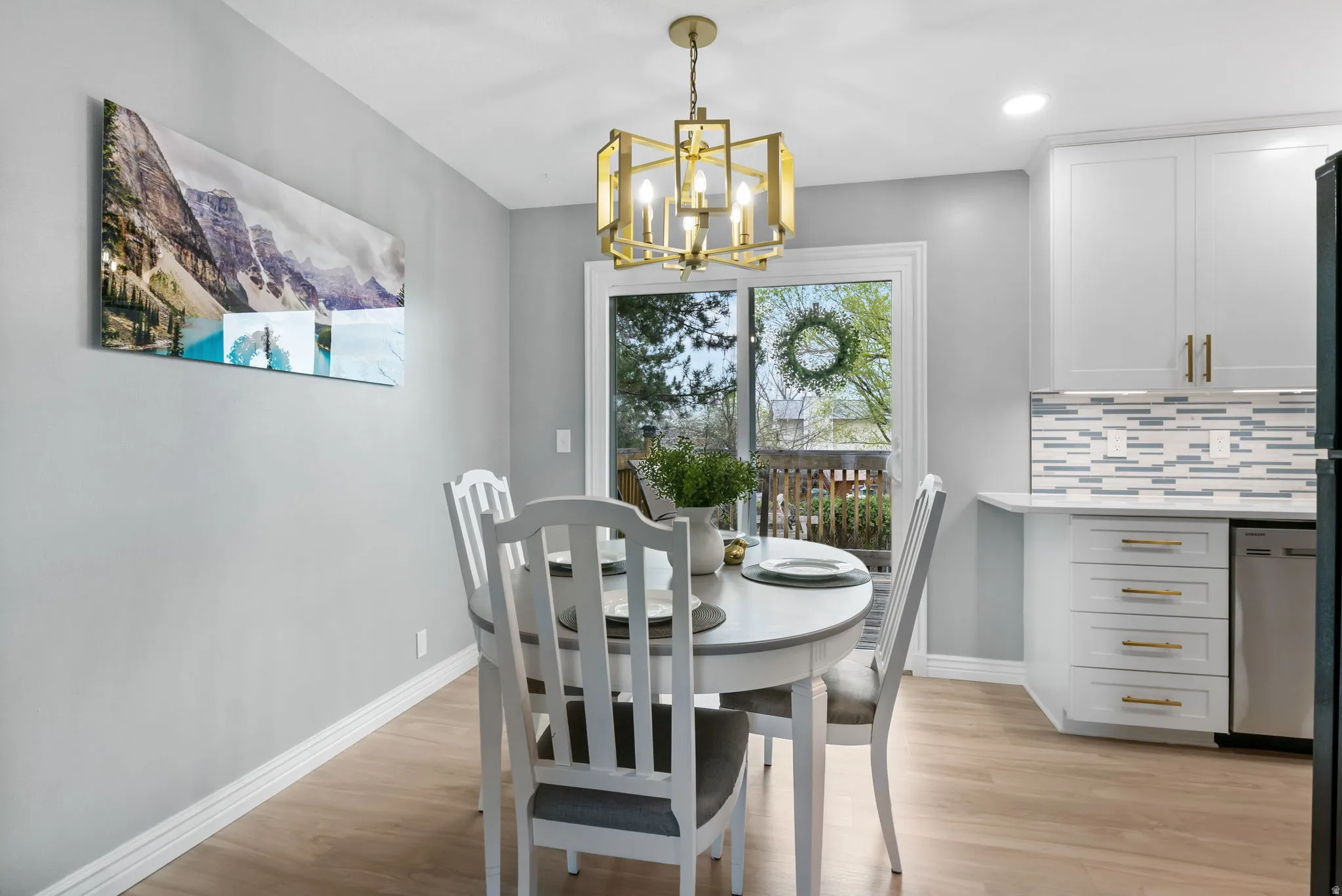 Dining area featuring wood-finish flooring, white baseboards, and a gold-tone geometric chandelier