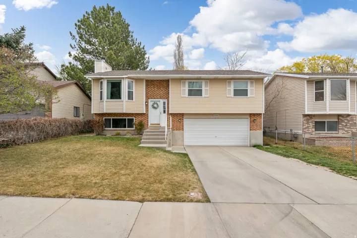 Split-level residence featuring a brick and siding exterior, an attached garage, a concrete driveway, a bay window, and a concrete pathway leading to the front entry