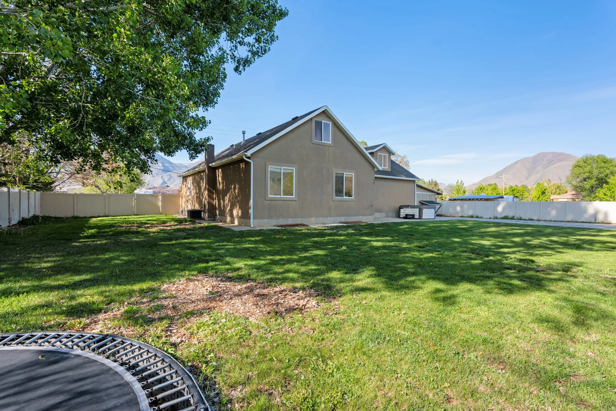 Expansive rear yard featuring green lawn, mature trees, and a privacy fence