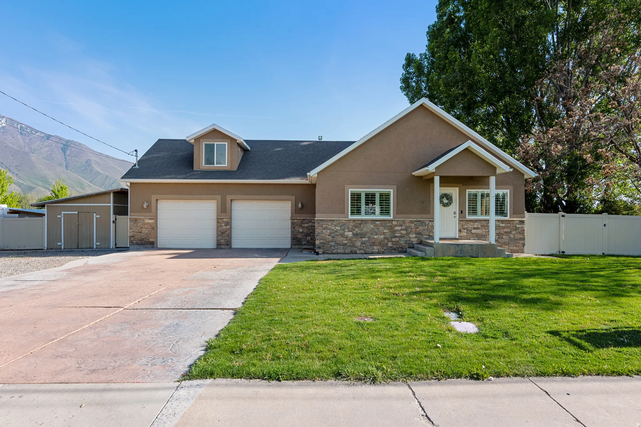 Front exterior featuring a two-car garage, stone veneer accents, and a covered porch entry