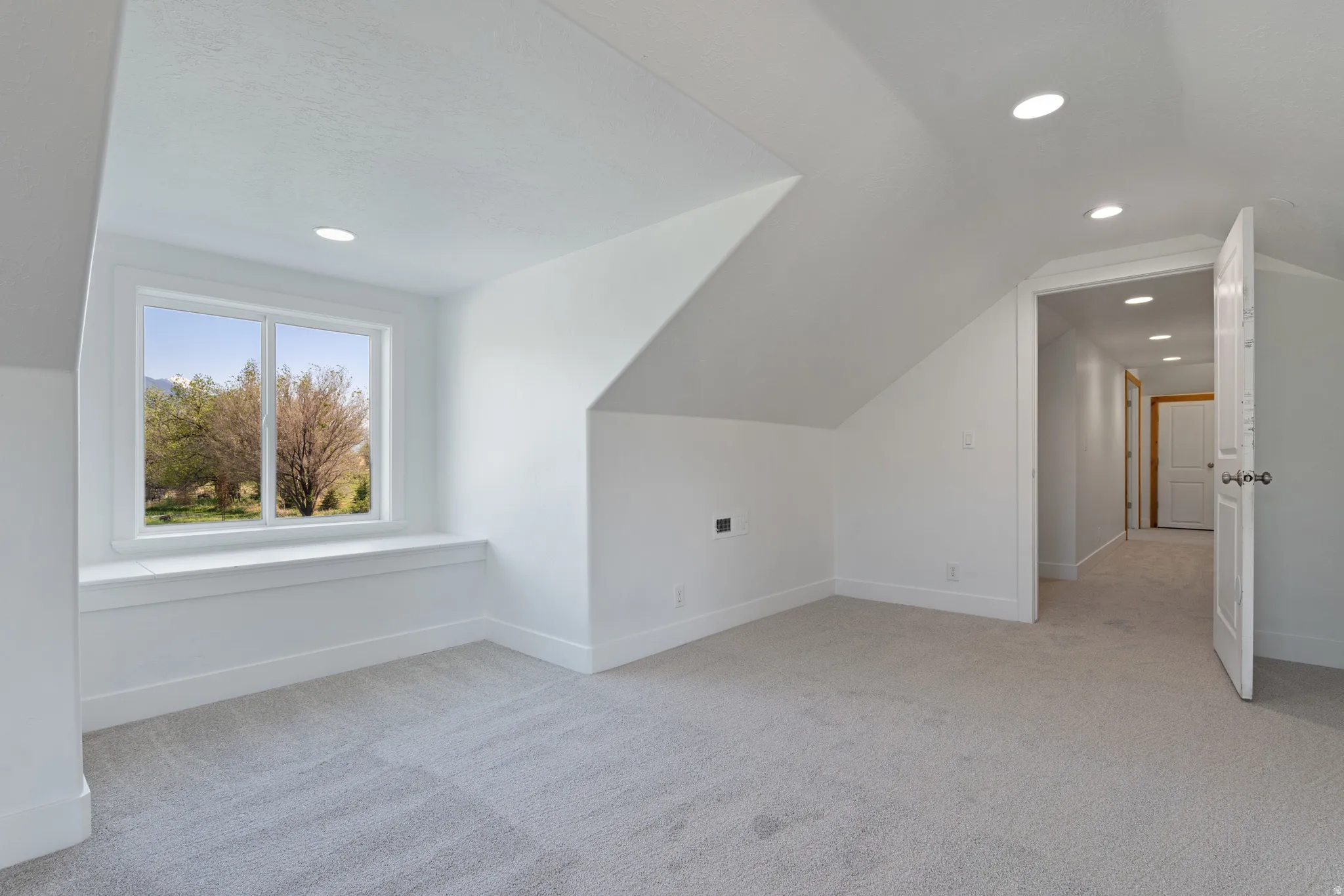 Carpeted room featuring a window with a built-in window seat, recessed lighting, and white trim