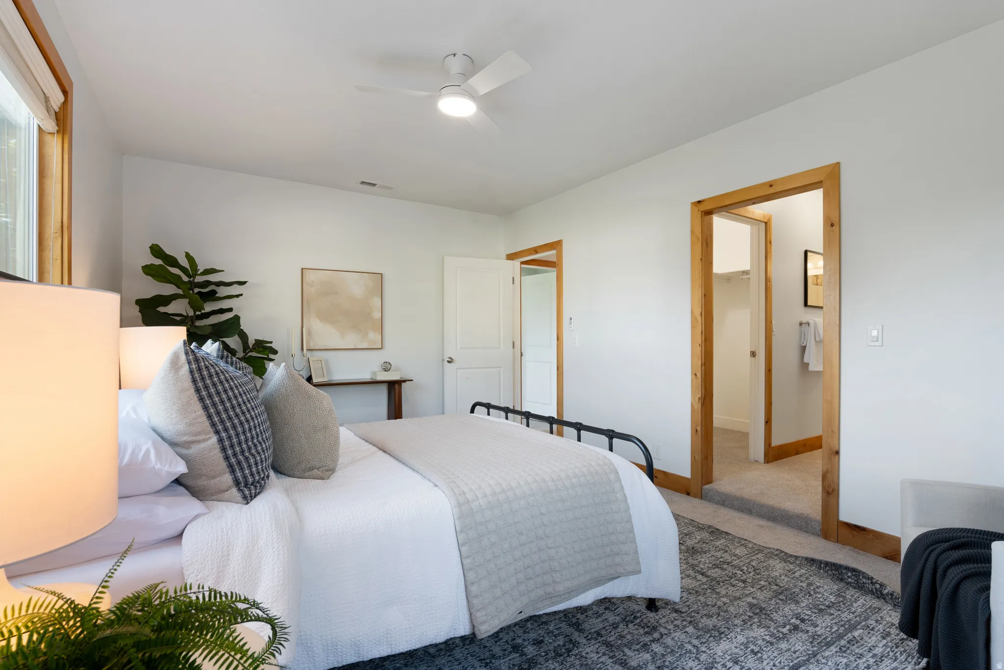 Bedroom featuring a vaulted ceiling with a ceiling fan, white walls, and wood-trimmed window