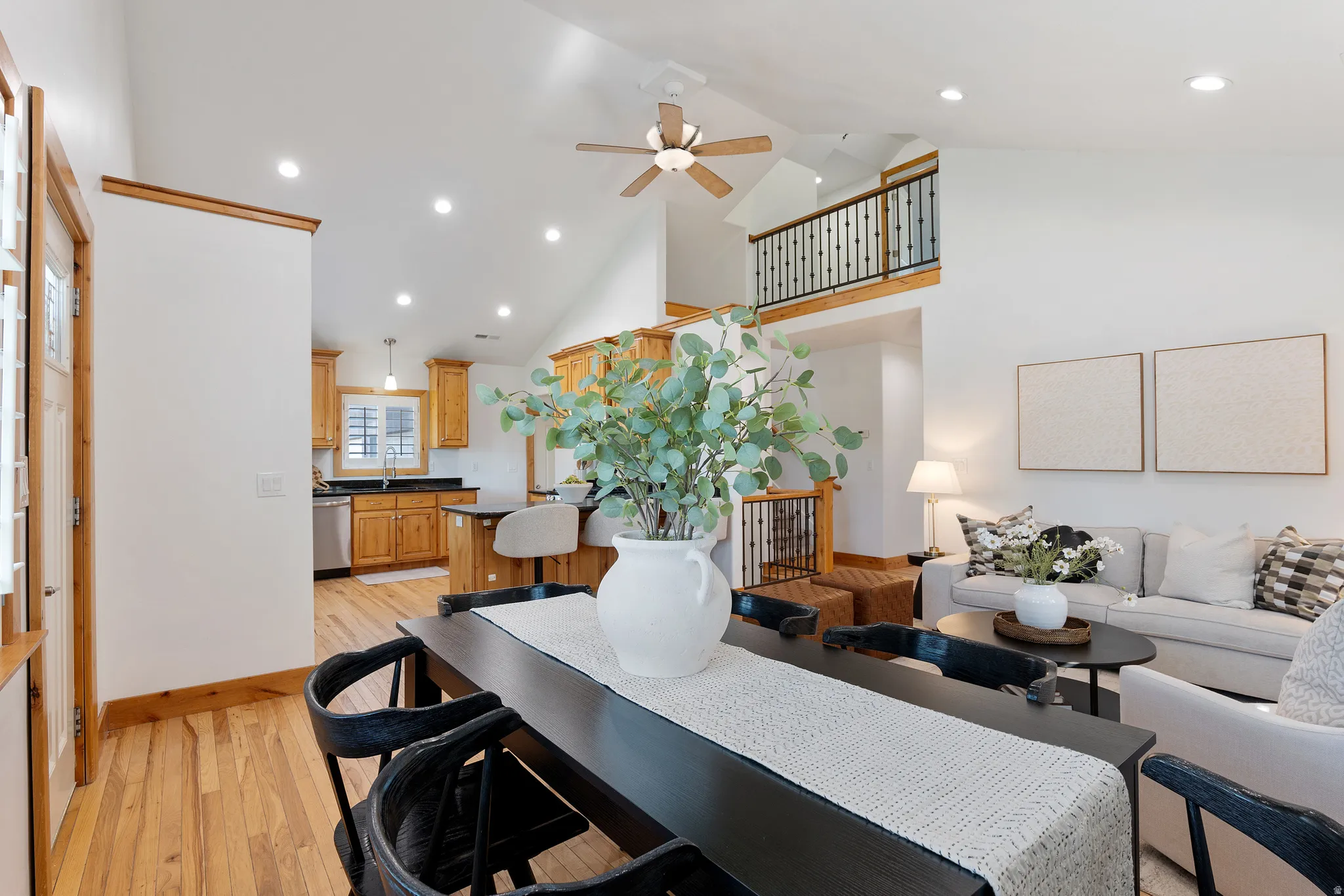Vaulted ceilings with recessed lighting, wood-finish flooring, and a kitchen featuring wood cabinetry and dark countertops