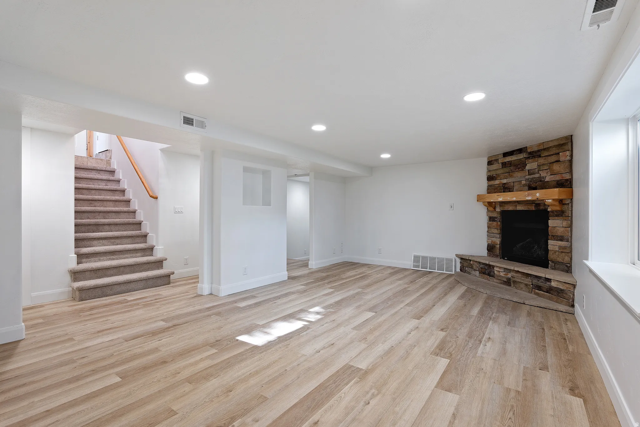 Spacious room featuring wood-finish flooring, recessed lighting, and white walls