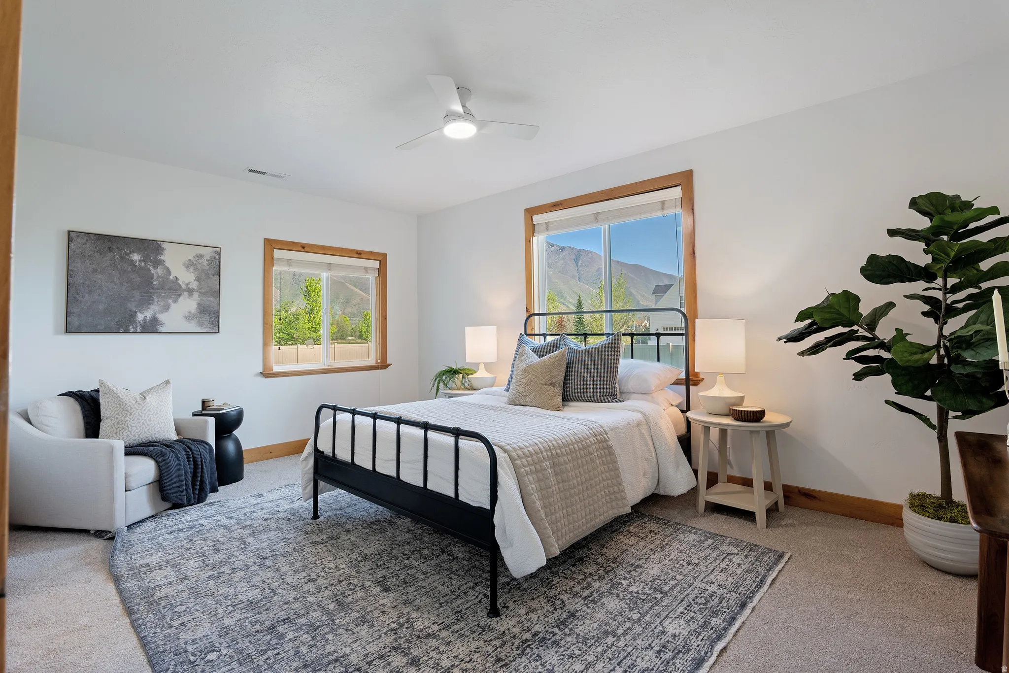 Bright room featuring two windows with wood trim, a contemporary ceiling fan, and carpet flooring