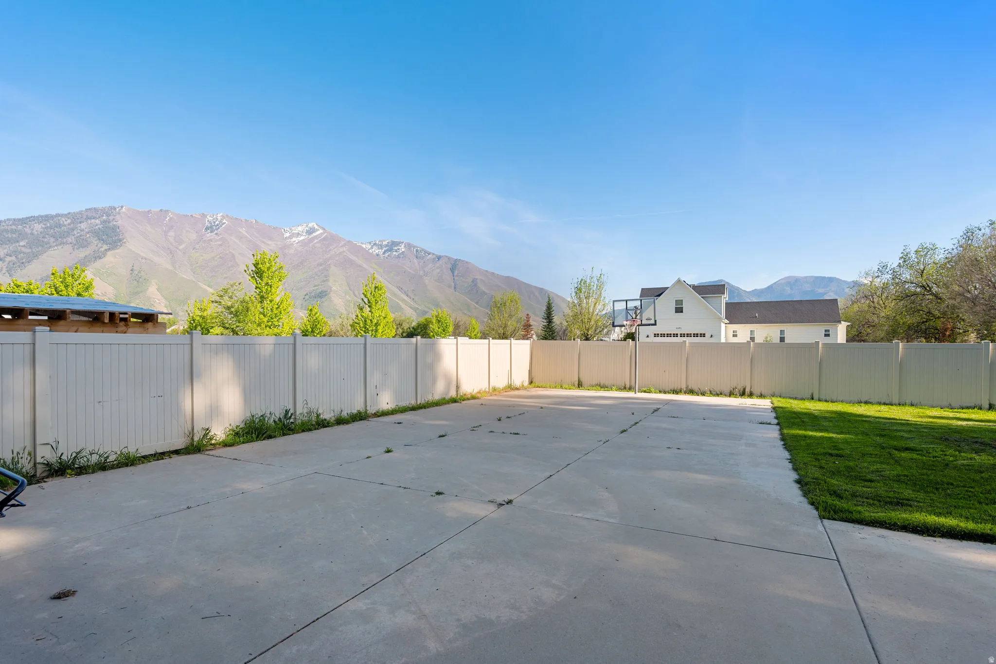 Expansive concrete pad bordered by a white privacy fence and a manicured lawn