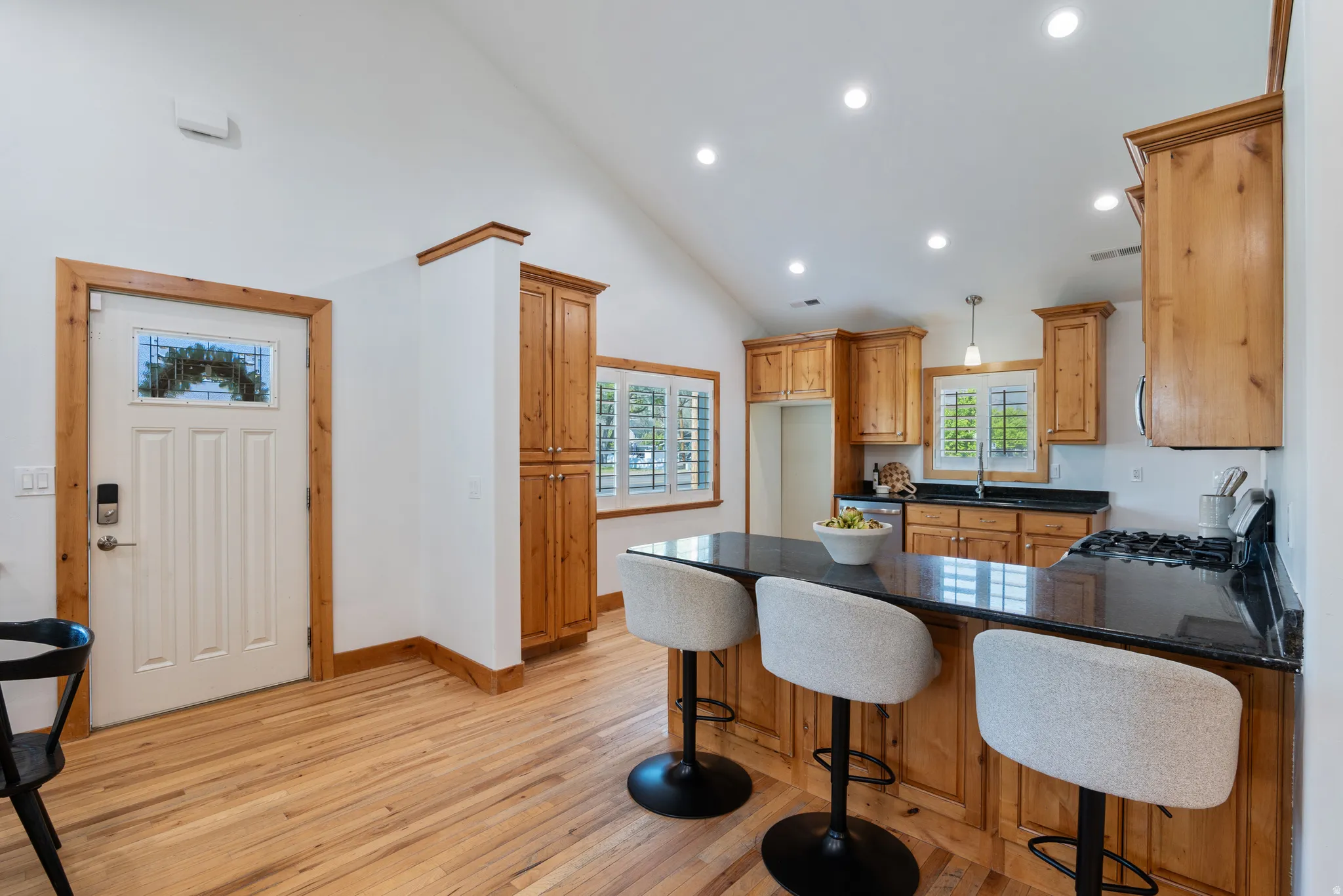Kitchen with wood-finish cabinetry, dark countertops, and a central island with integrated seating