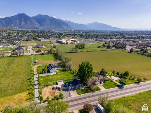 Expansive natural landscape featuring distant mountains with snow-capped peaks, surrounding green fields, and established residential areas