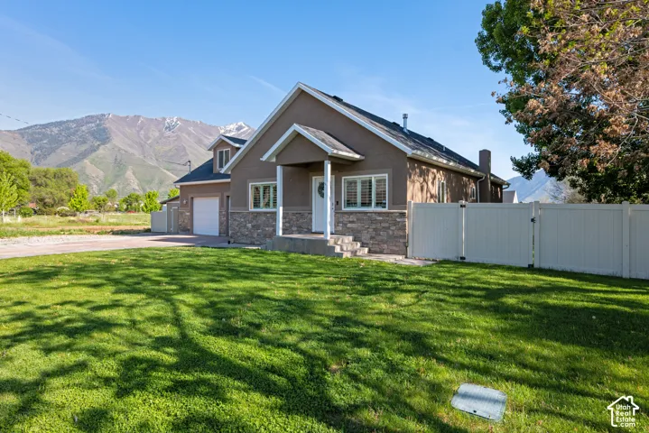 Stucco and stone facade home featuring a covered front porch with white columns, a two-car garage, and a fenced backyard
