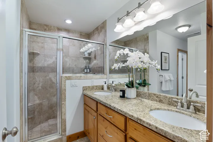 Bathroom featuring a spacious dual vanity with a granite countertop, light wood cabinetry, and a large mirror