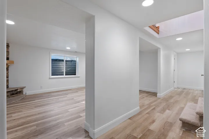 Brightly lit interior space featuring wood-finish flooring, recessed lighting, and a stone-clad fireplace with a wood mantel