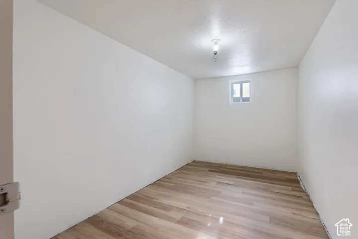 Room with light wood-finish flooring, white walls, and a single window