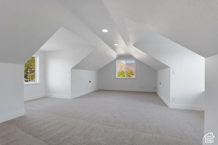 Spacious upper-level room featuring angled ceilings, recessed lighting, and light gray carpeting