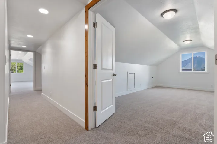 Carpeted room with a vaulted ceiling and a double-pane window