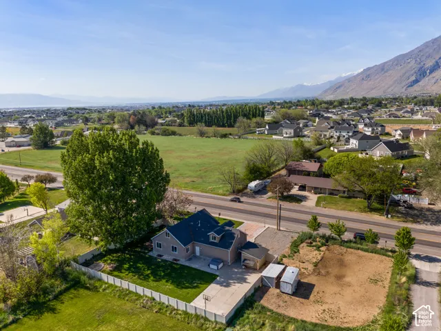 Aerial overview showcasing a residential property with a partial white fence, a basketball hoop on the driveway, and a detached two-car garage