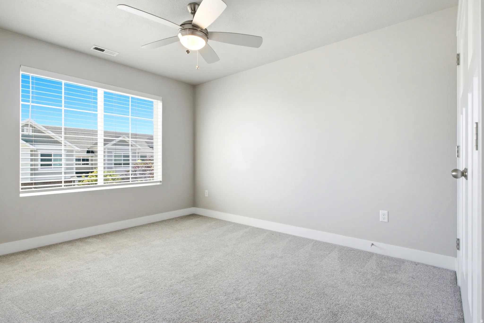 Spacious room featuring light gray carpeting and neutral wall tones