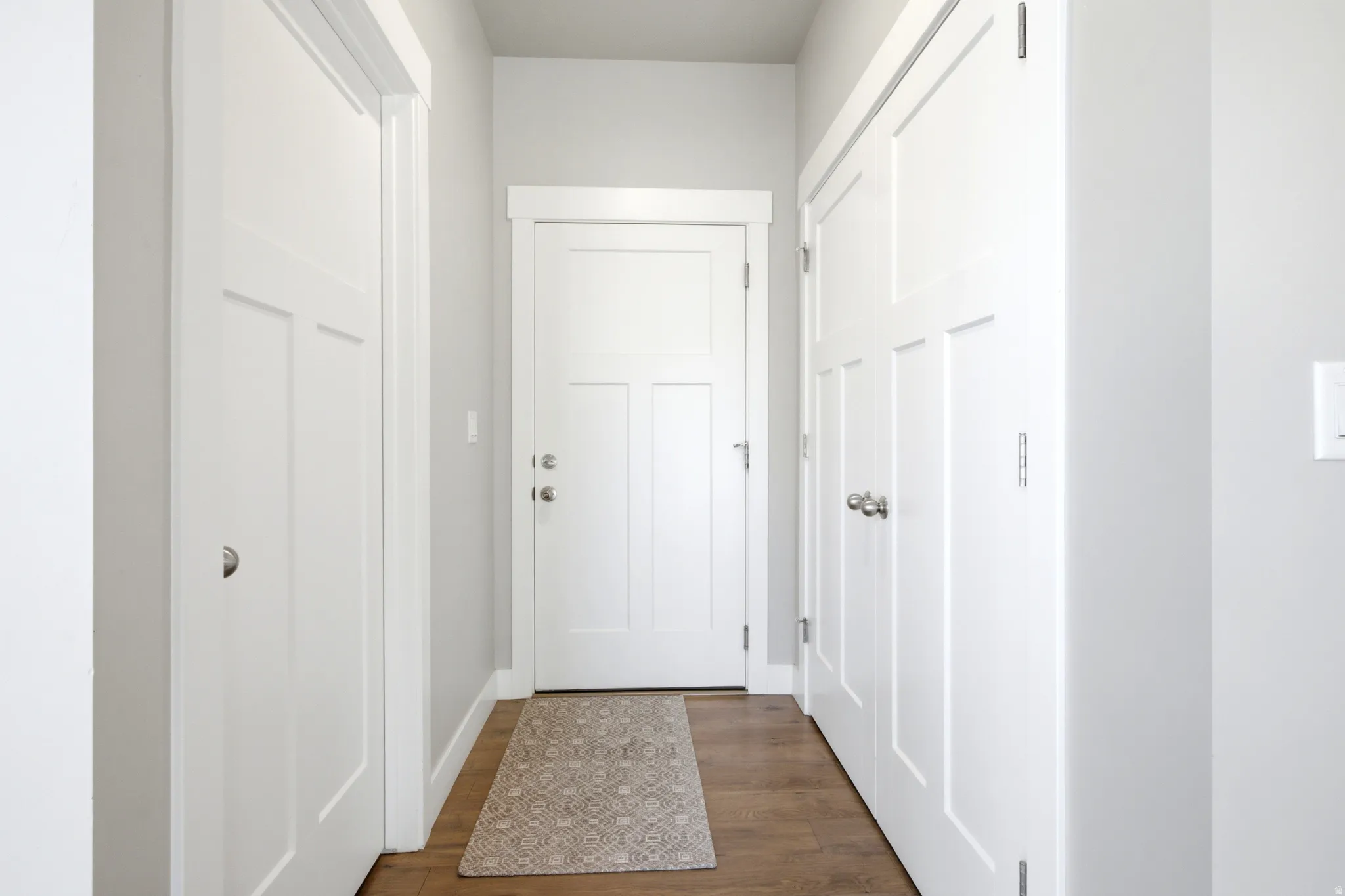 Entryway featuring craftsman-style white doors, wood-finish flooring, and light gray wall paint