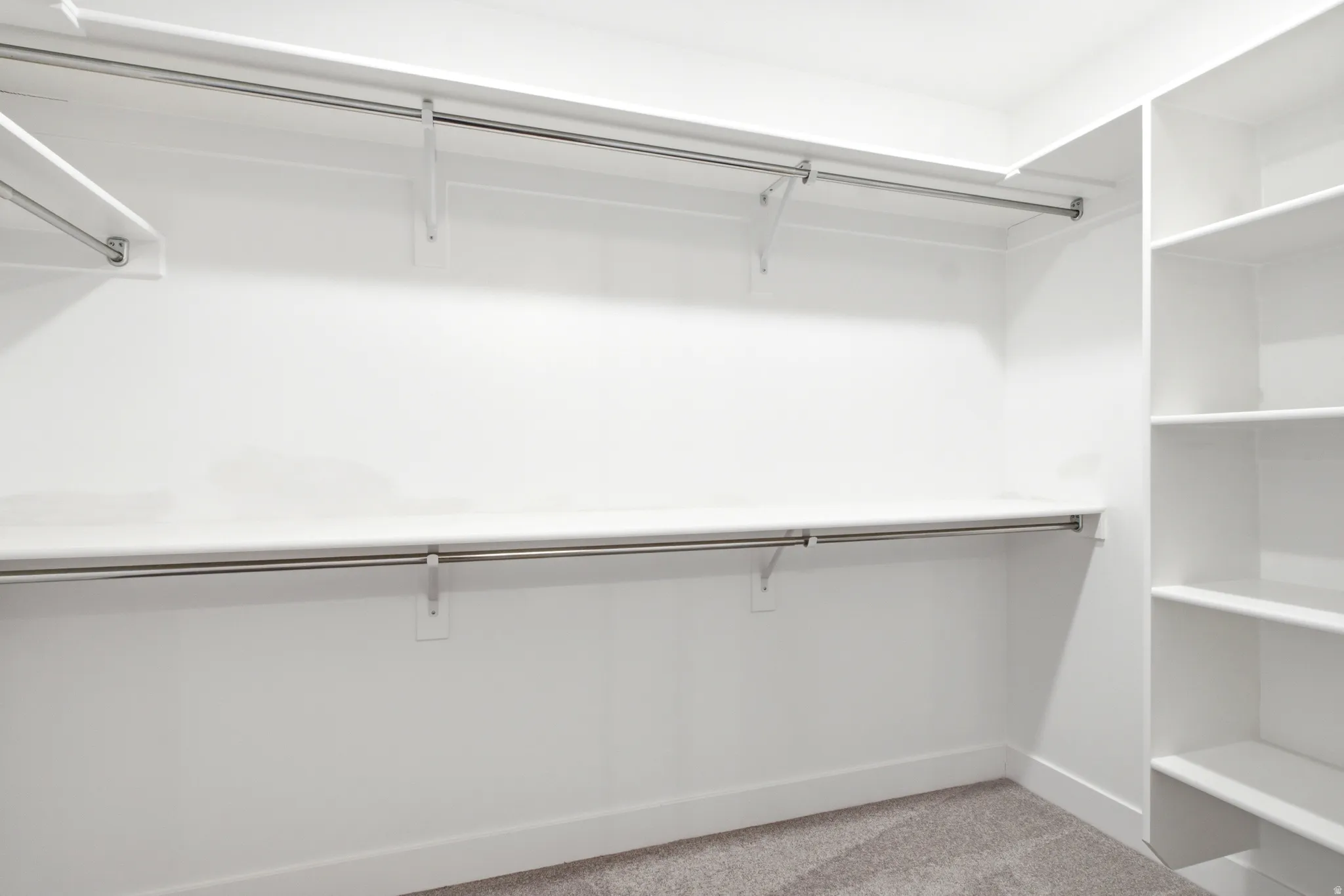 Custom closet system featuring white shelving, multiple hanging rods, and built-in shelving units