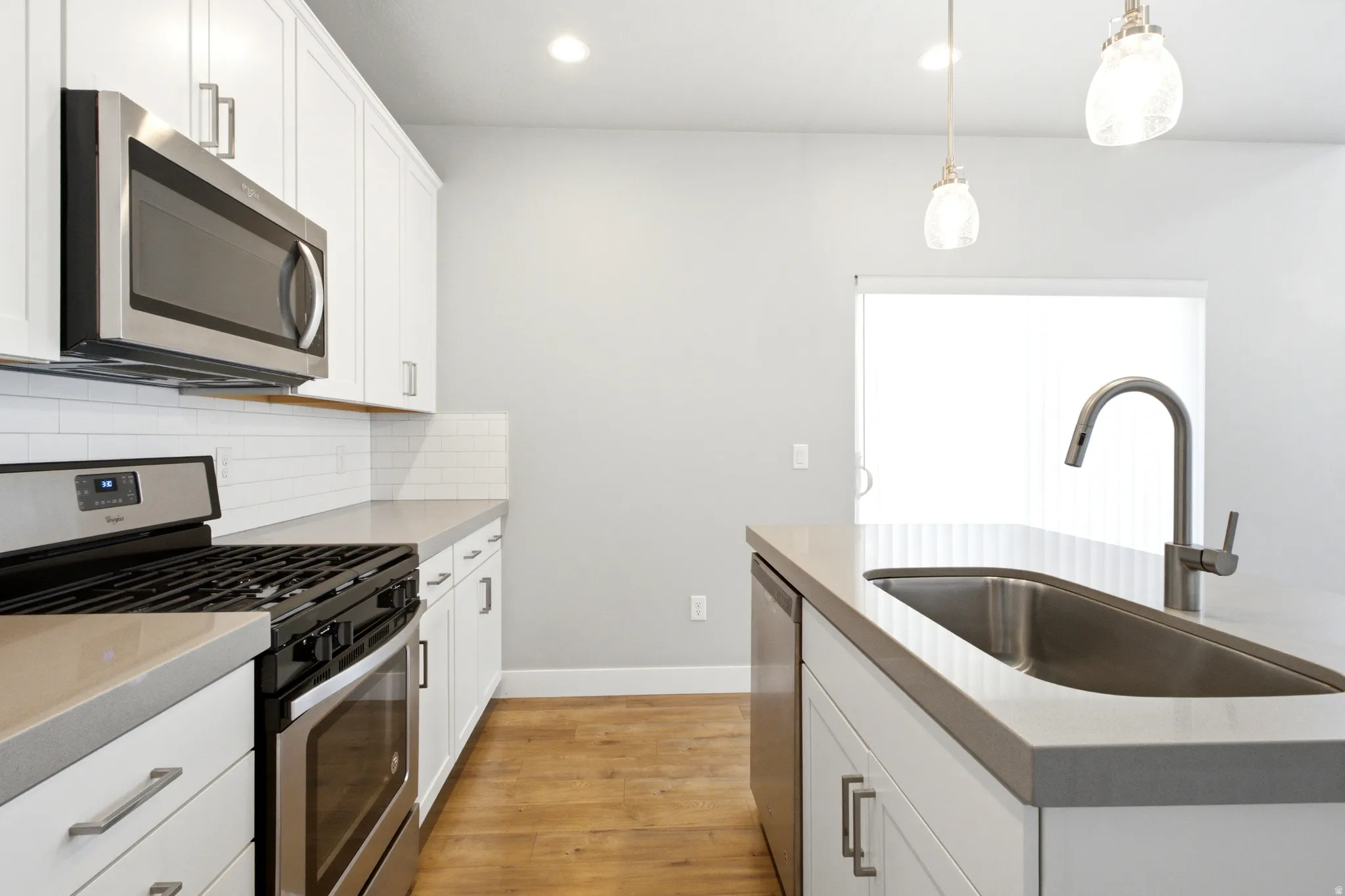 Modern kitchen featuring white shaker cabinetry and light countertops