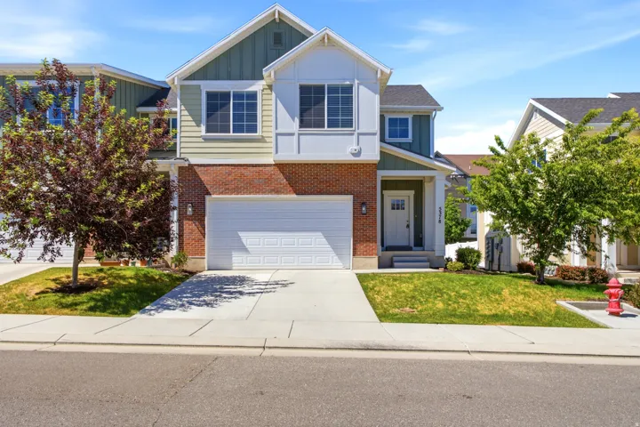 Two-story residence featuring brick and siding facade, an attached garage, covered entryway, and front yard landscaping