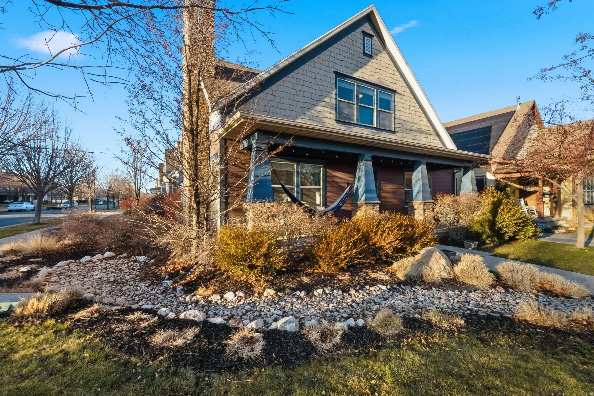 Gable-front home featuring a covered front porch with blue columns, wood-look siding, and shingle siding accents