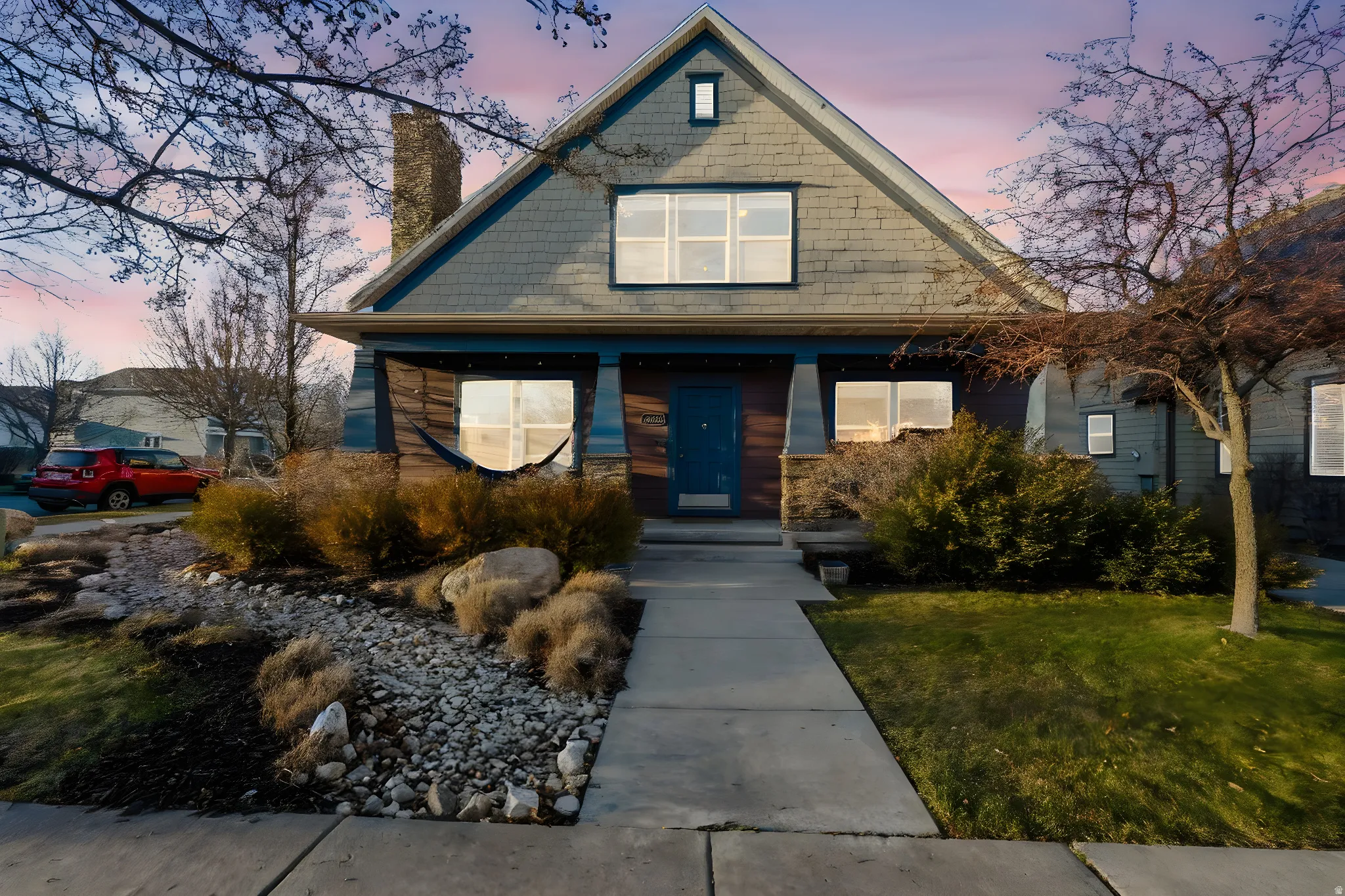 Gable-front home featuring shake-style siding, a covered porch, and a prominent chimney