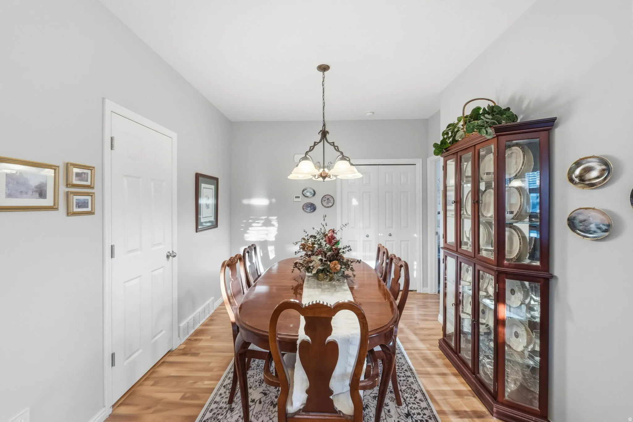 Dining area with wood-finish flooring, light gray wall paint, and a traditional chandelier
