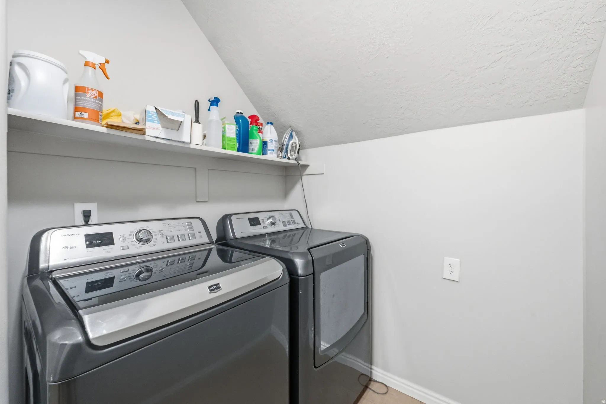 Dedicated laundry space with light gray walls, a built-in white shelf, and wood-finish flooring