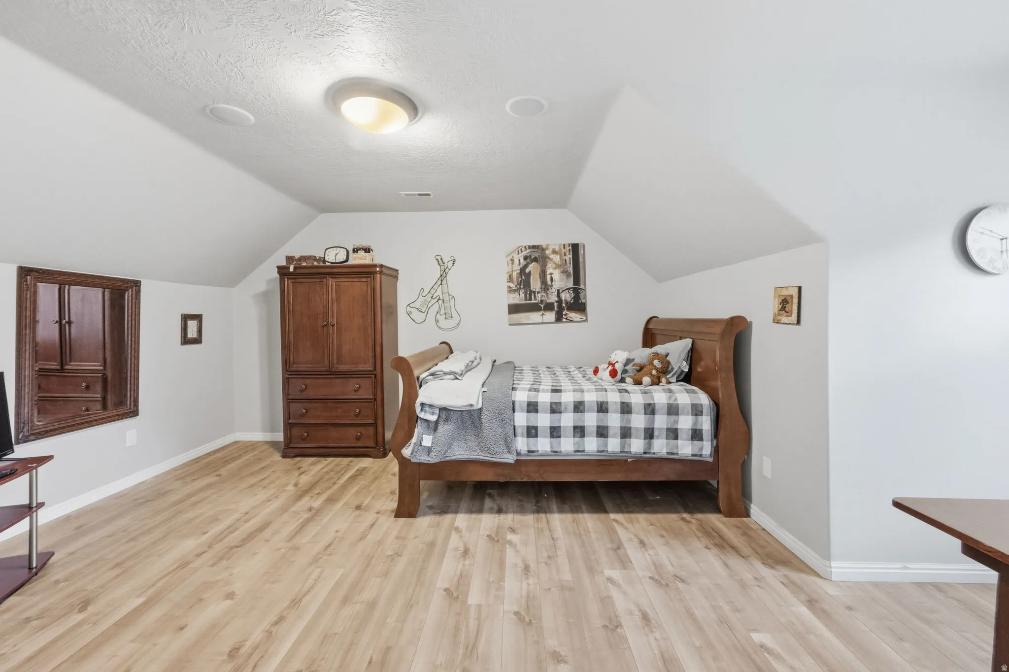 Spacious room featuring vaulted ceilings, light wood-finish flooring, recessed lighting, and a flush-mount ceiling light
