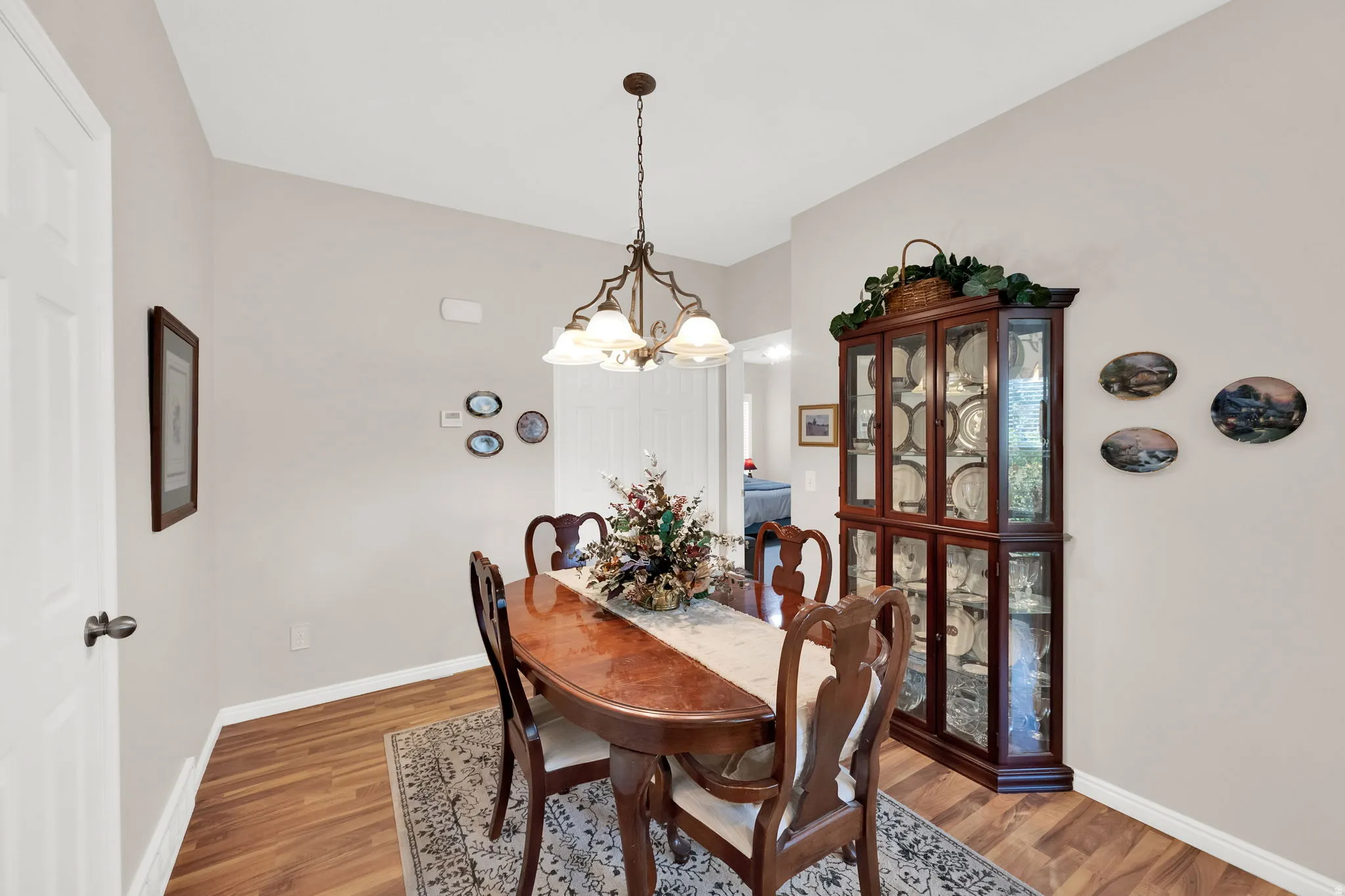 Dining area featuring wood-finish flooring, a traditional chandelier, and light neutral wall paint