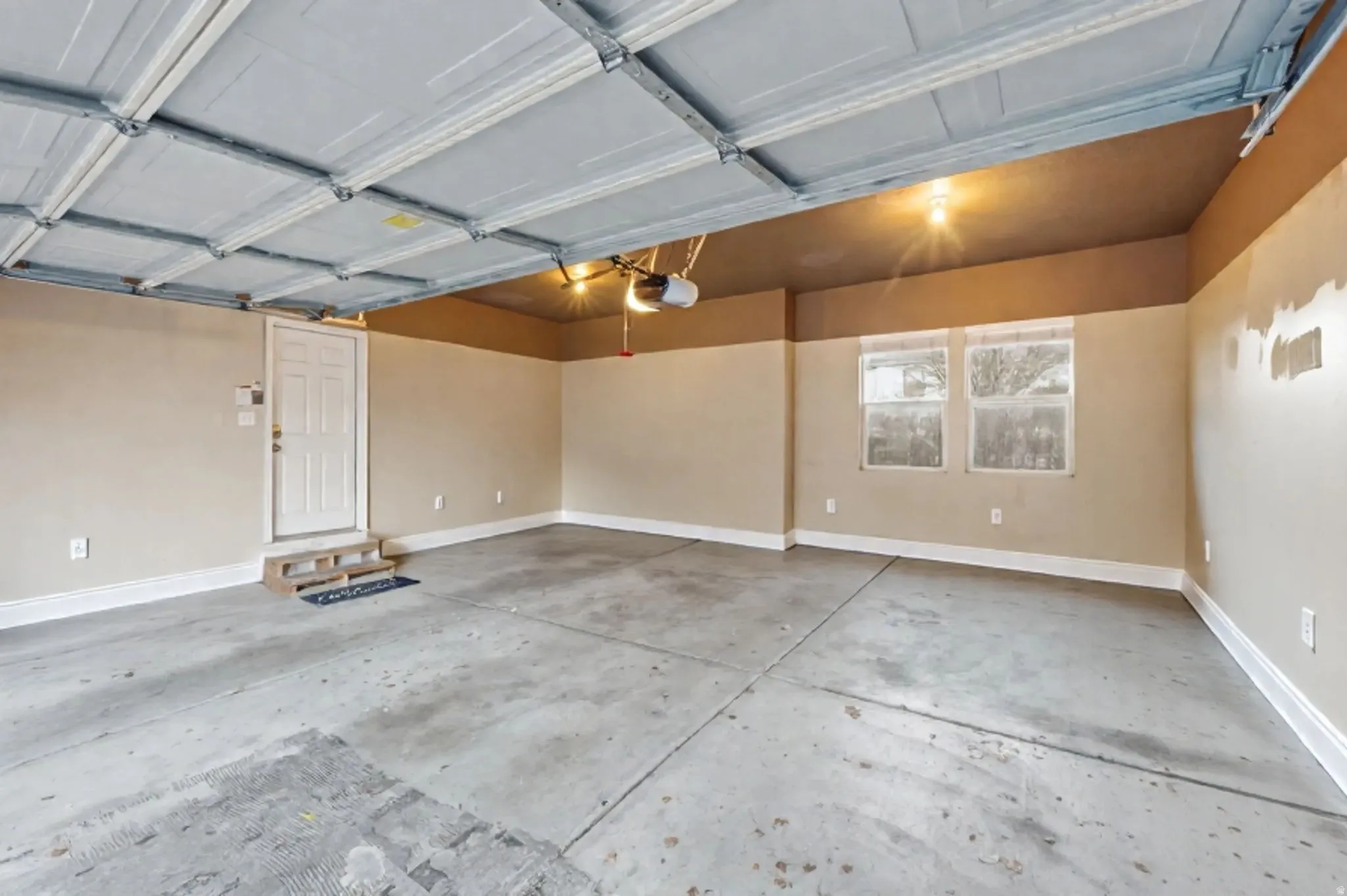 Spacious garage featuring a concrete floor, light-colored walls, white trim, and two windows providing natural light