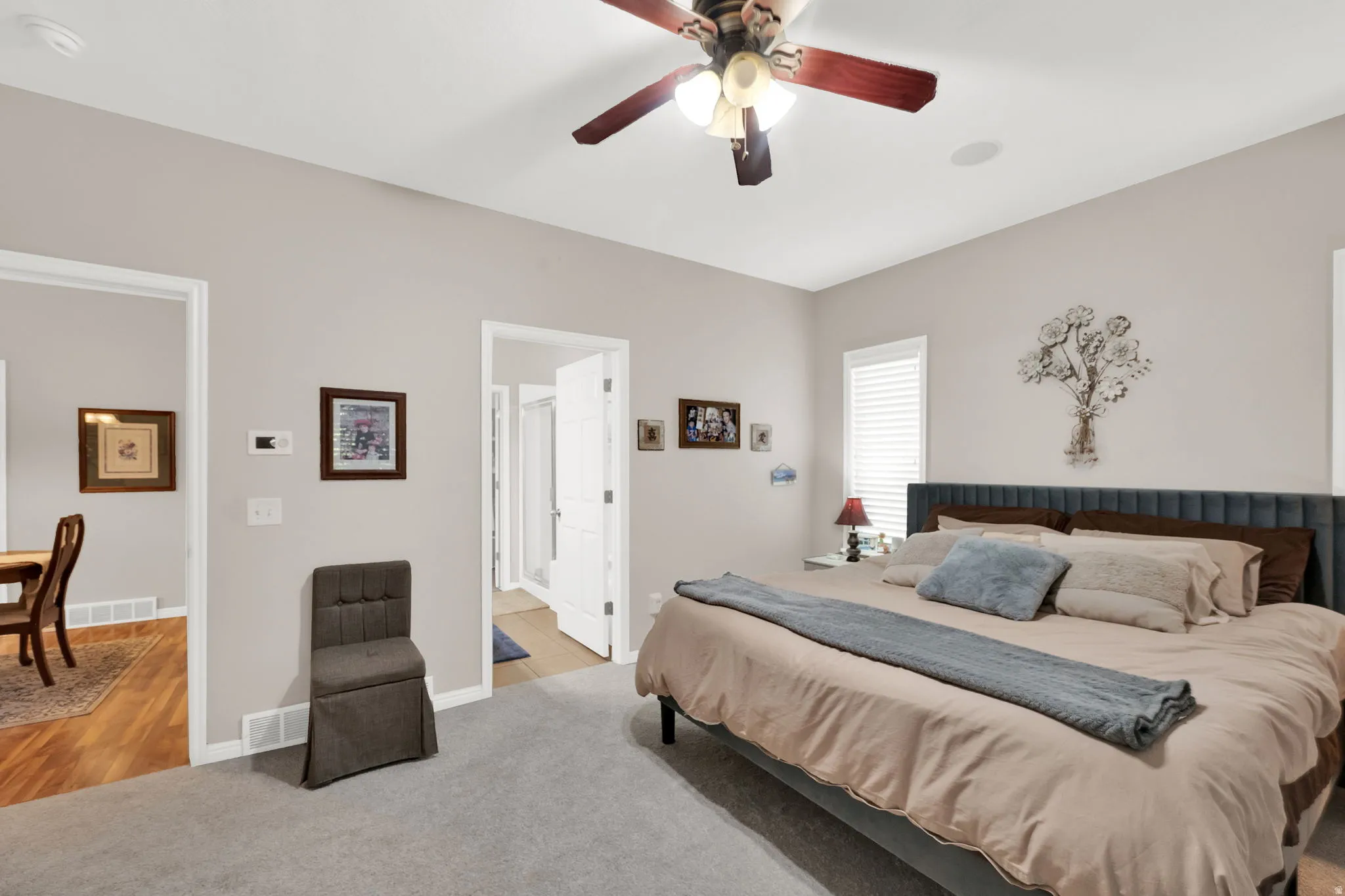 Spacious bedroom featuring light grey wall paint and grey carpeting