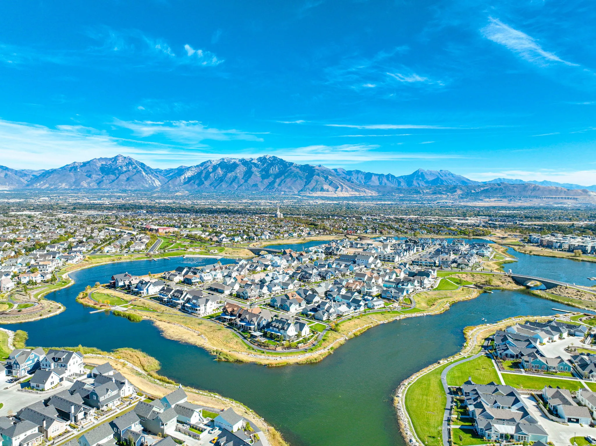 Aerial perspective showcasing a residential community with winding waterways, surrounding homes, and distant mountains