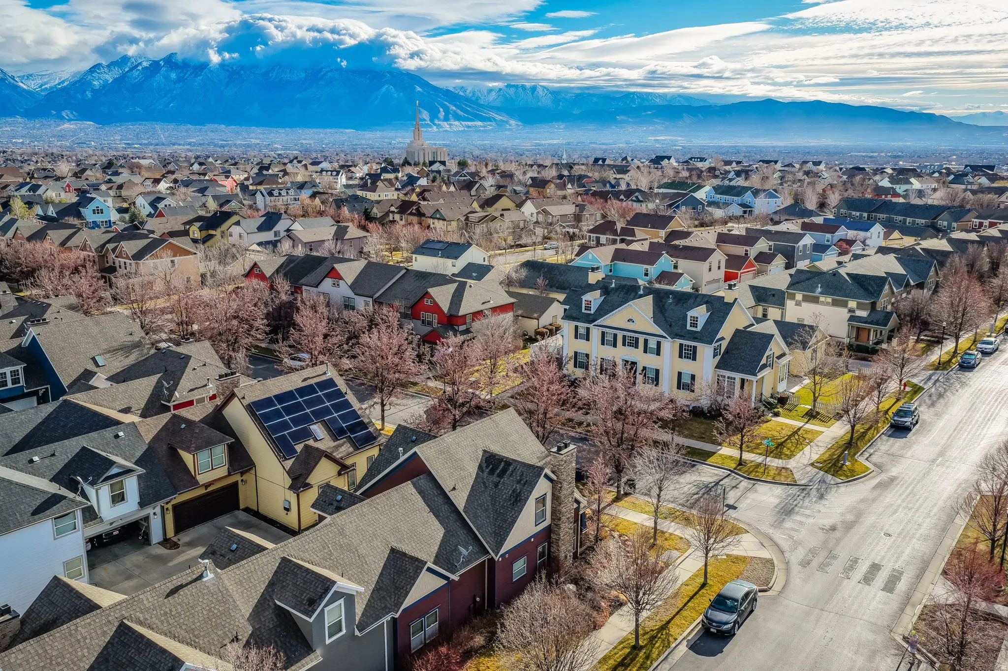 Residential neighborhood featuring a variety of architectural styles, mature trees, and mountainous terrain in the background