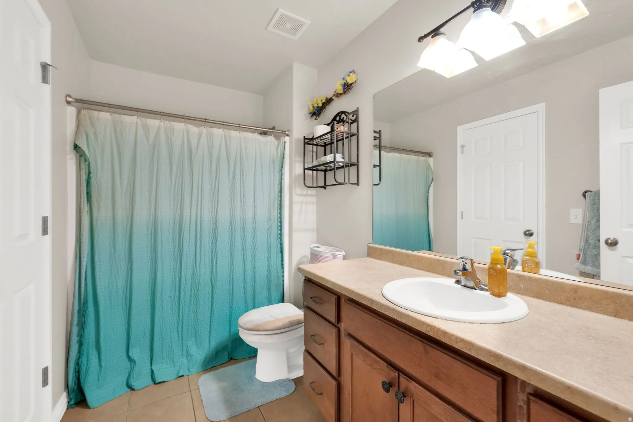 Bathroom featuring a single vanity with an integrated sink, a large wall-mounted mirror, and a shower with a curtain rod