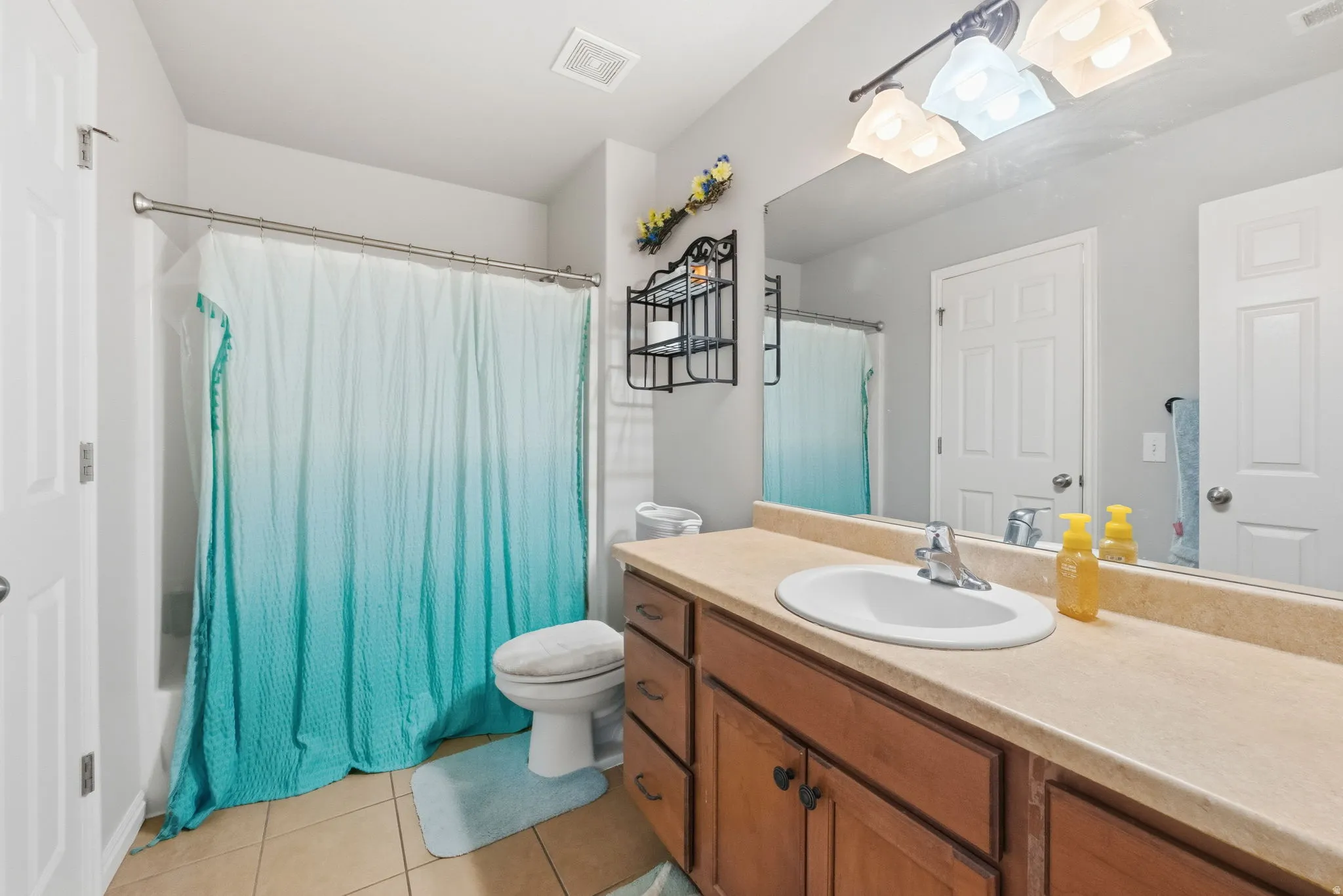 Bathroom featuring a vanity with a light-toned countertop, wood-finish cabinetry, and a mirrored wall