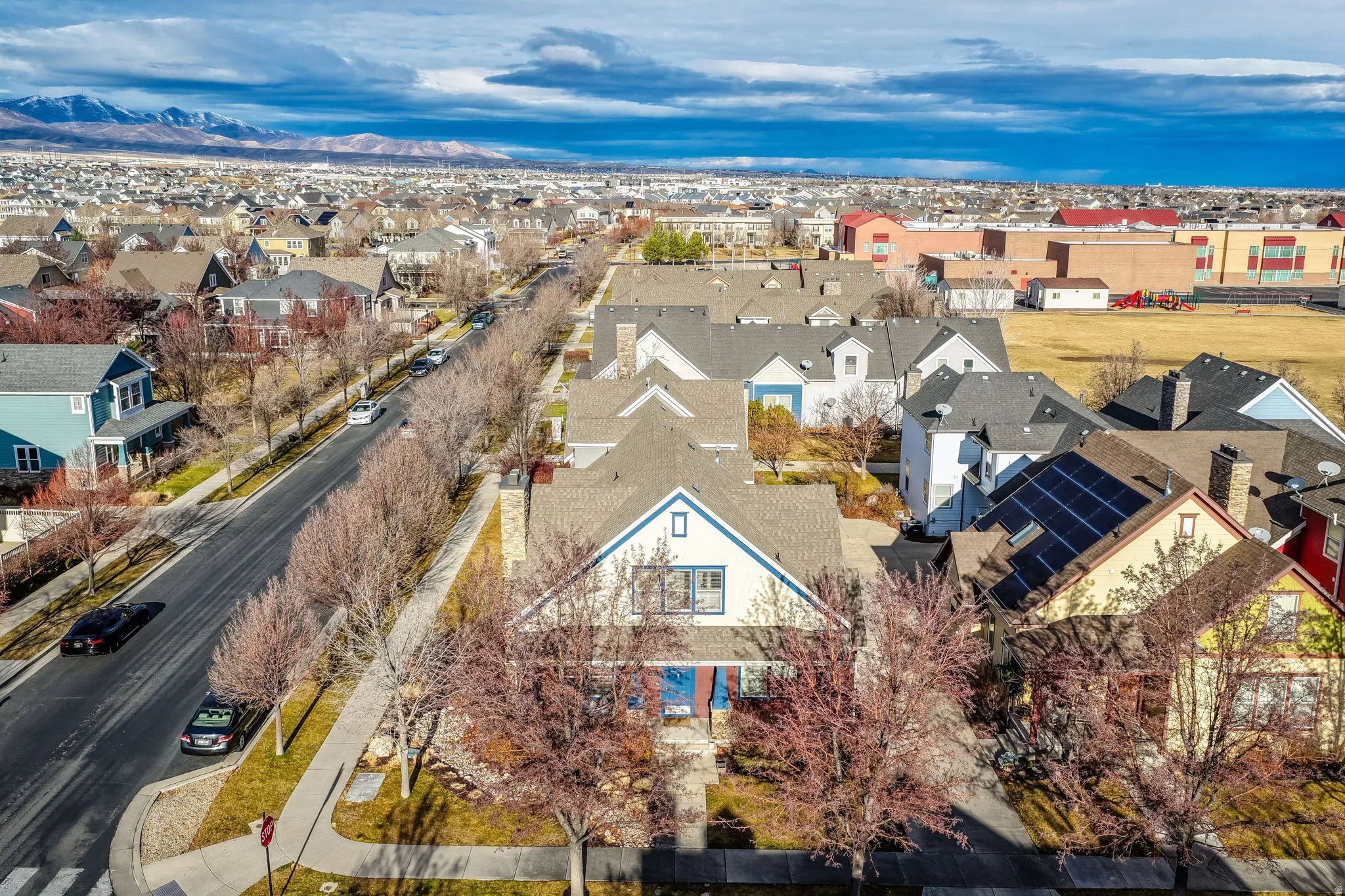 Residential neighborhood with a mountain backdrop, featuring a street lined with deciduous trees