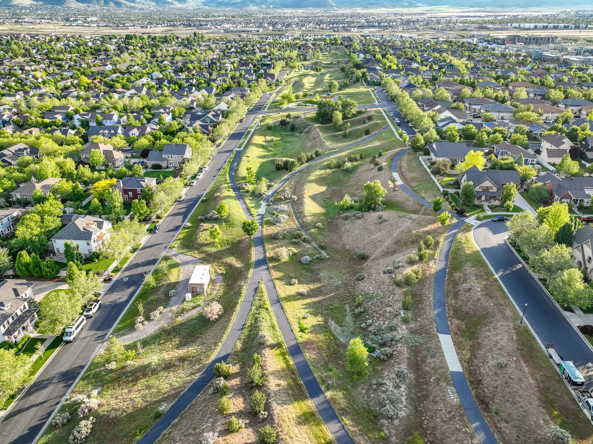 Expansive residential area featuring numerous detached homes with diverse architectural styles, tree-lined streets, and a prominent central green space