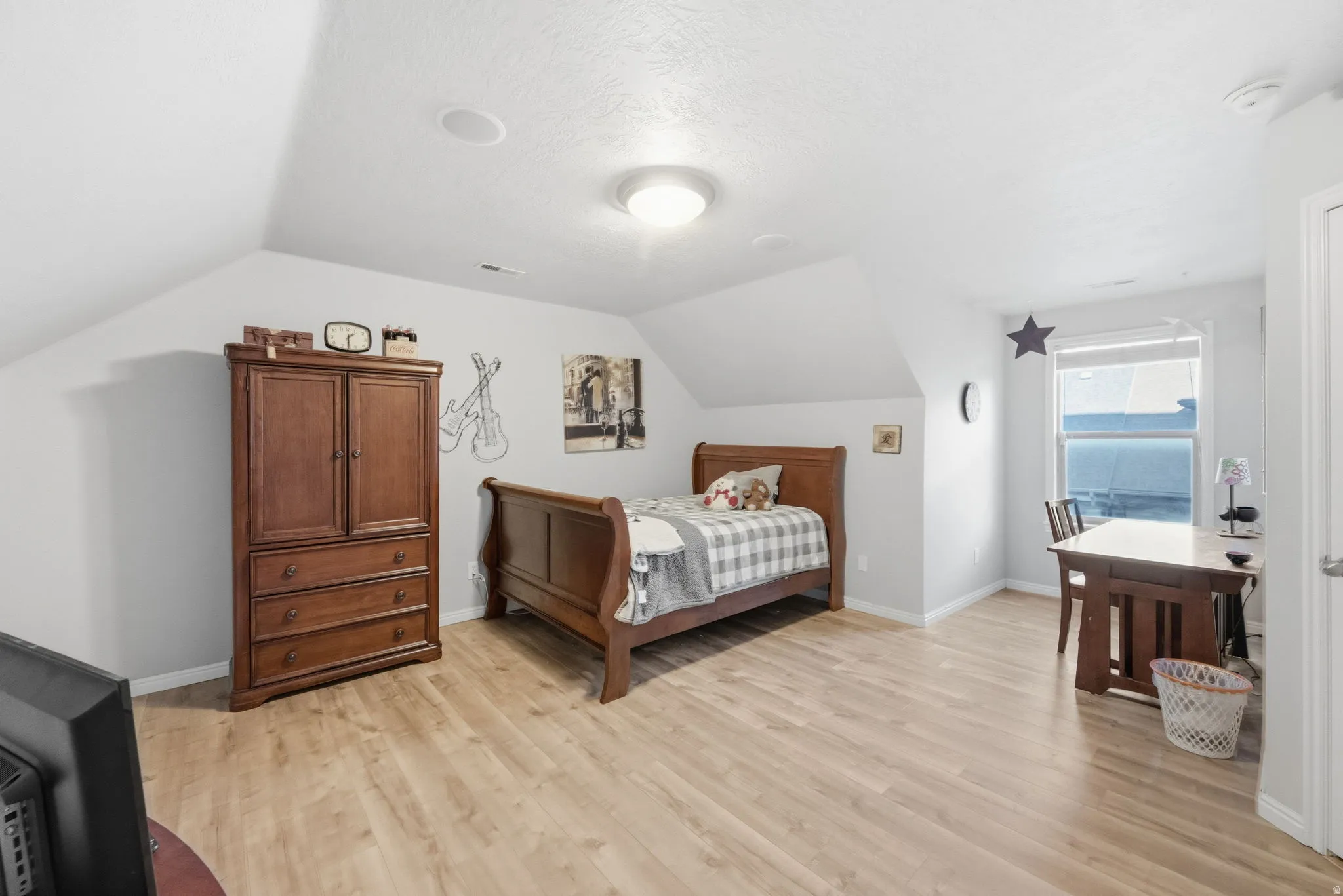 Spacious room featuring vaulted ceilings, light wood-finish flooring, a contemporary flush mount light fixture, and recessed lighting
