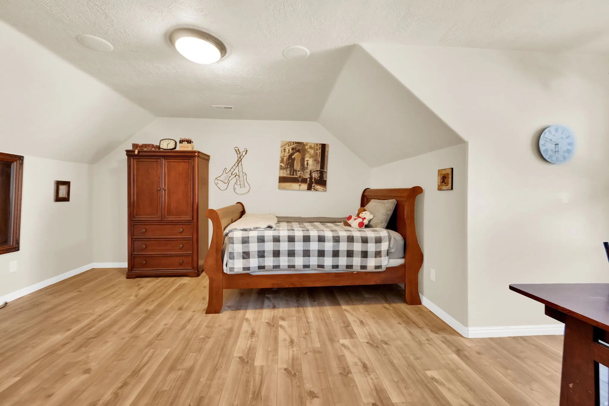 Vaulted ceiling room featuring wood-finish flooring, recessed lighting, and a built-in window frame with wood trim