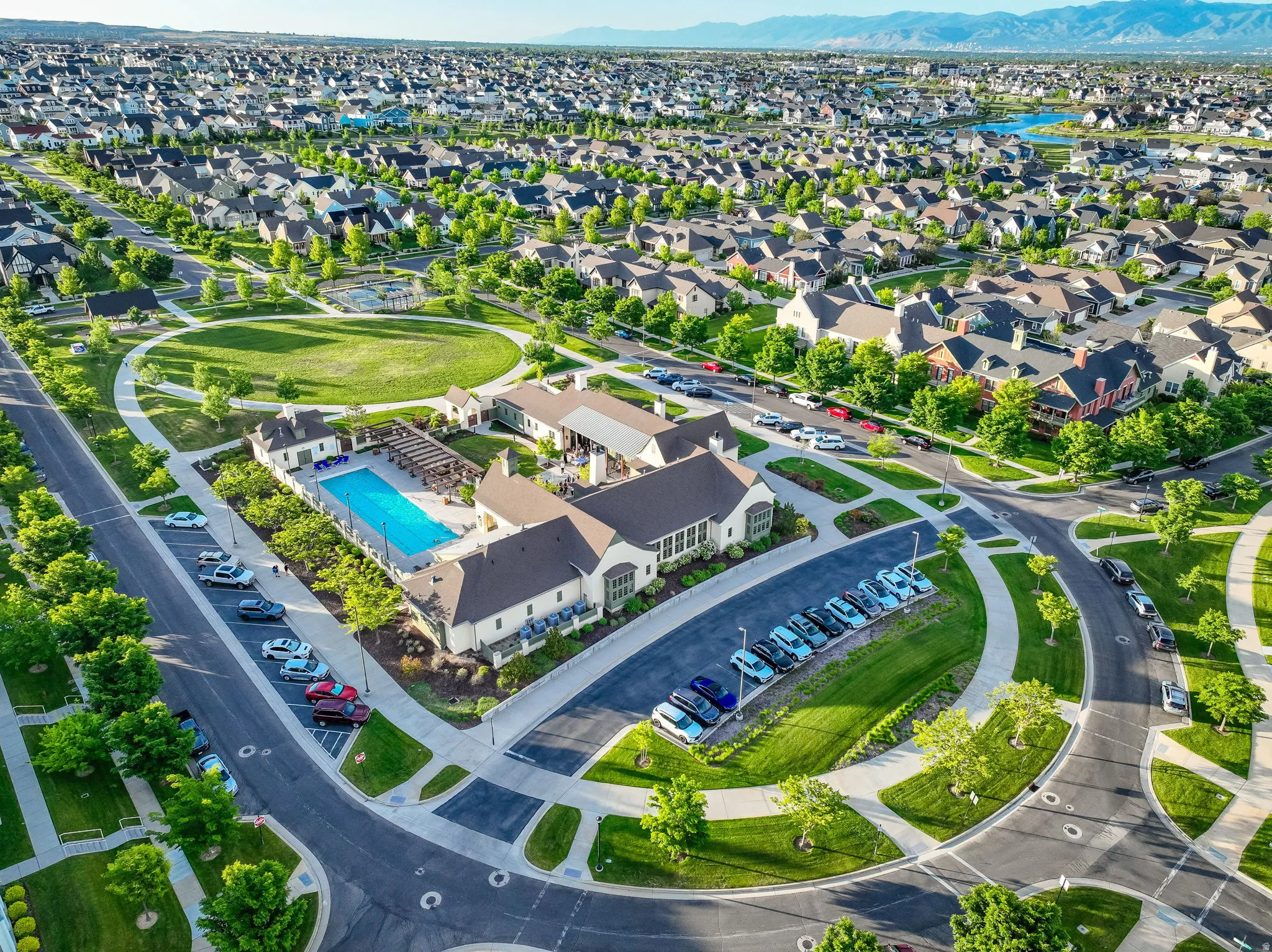 Community amenity center featuring an outdoor swimming pool, pergola-covered lounge area, and a surrounding green space
