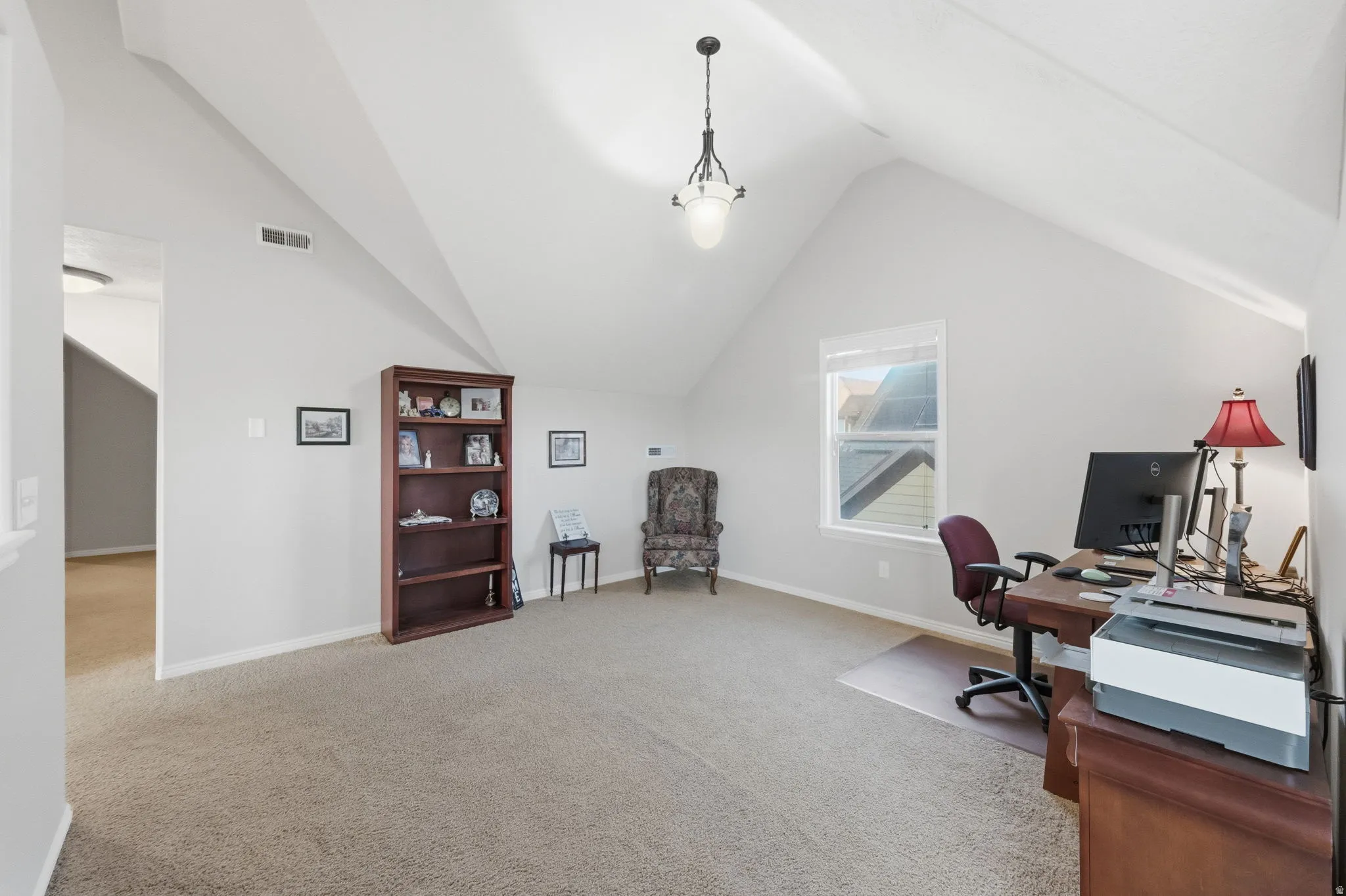 Spacious bonus room featuring an angled vaulted ceiling, carpet flooring, and a single window