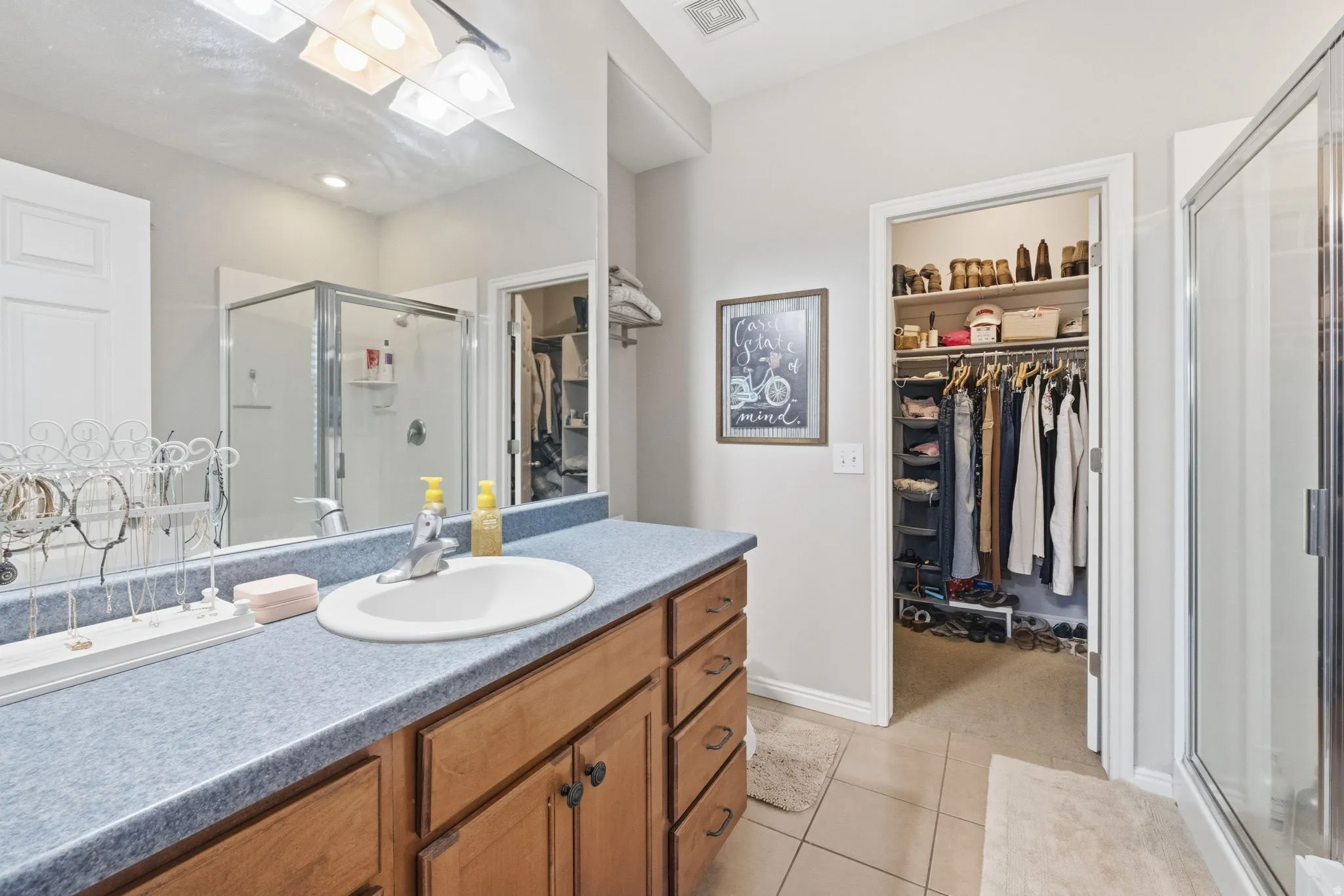 Bathroom featuring a single vanity with wood cabinetry, a light blue countertop, and an integrated white sink