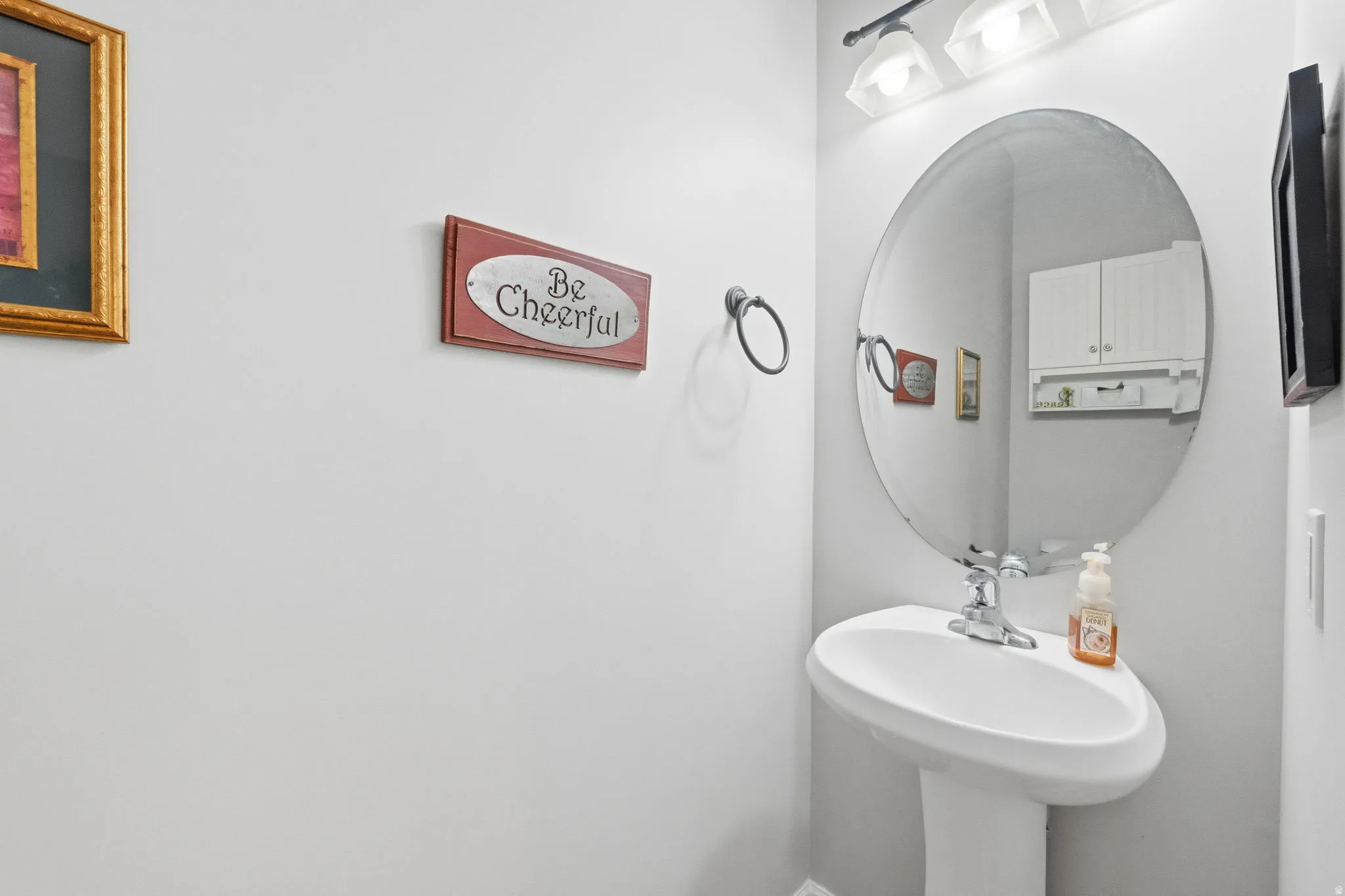 Pedestal sink with chrome faucet, complemented by a large oval mirror