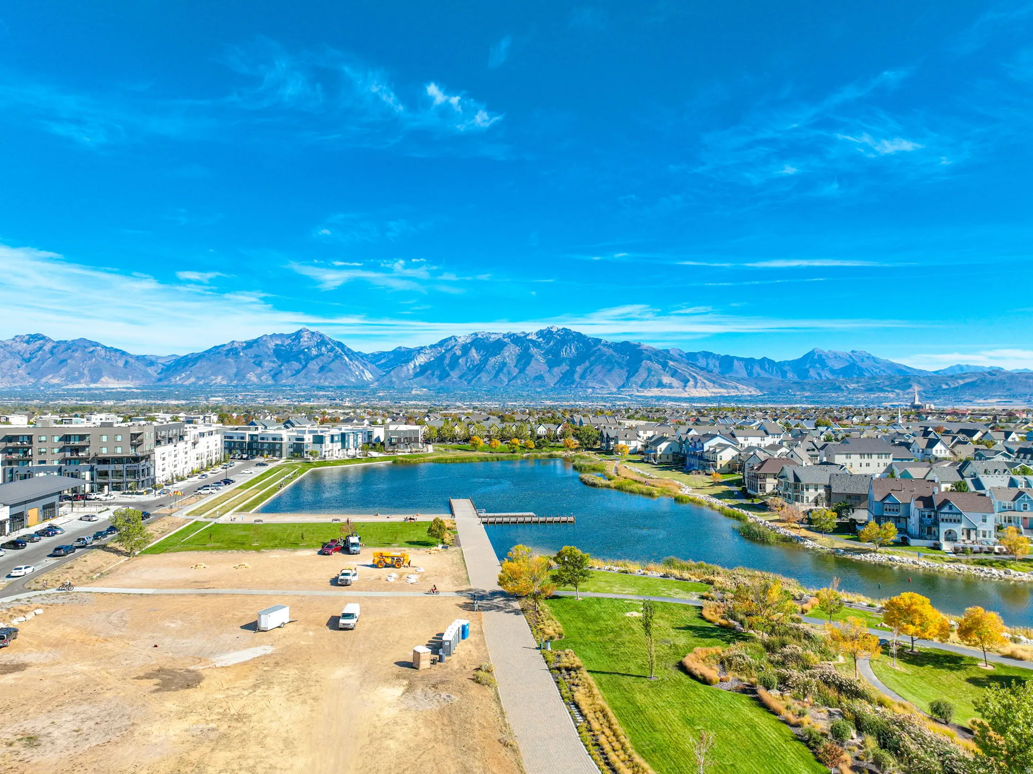 Lakeside community featuring a mountain backdrop, a prominent pier, and established residential areas